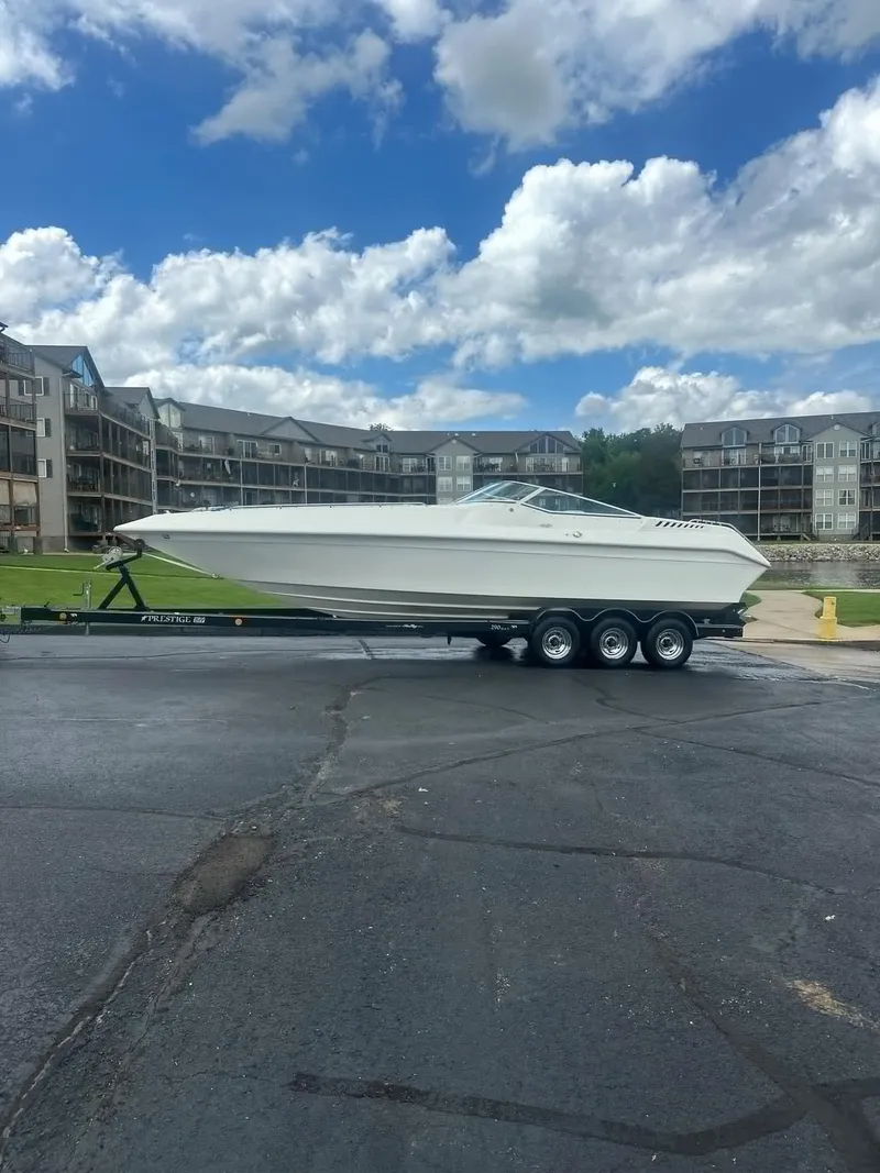 Slide: The Image of 1998 Envision 2900 Combo boat on trailer, parked outdoors under a cloudy sky. - 44