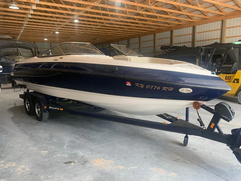 Slide: The Image of 2003 Bryant 232 RB boat in storage, blue and white, on a trailer. - 1