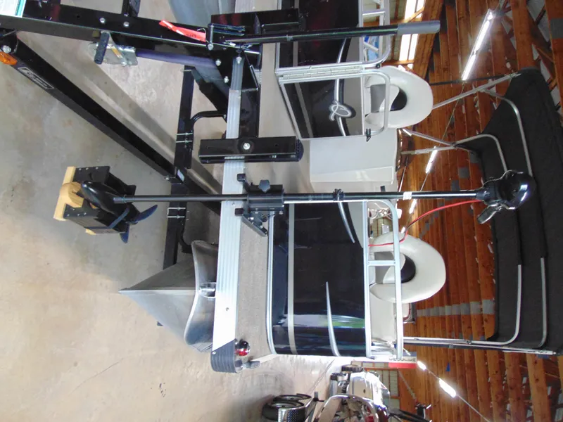 Slide: The Image of 2012 Apex Marine 1716 pontoon boat in storage, featuring black and white design. - 7