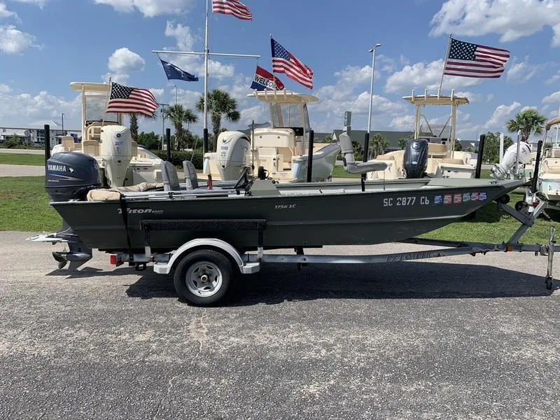 Slide: The Image of 2007 Triton 1756S boat on trailer, parked outdoors with flags in the background. - 4