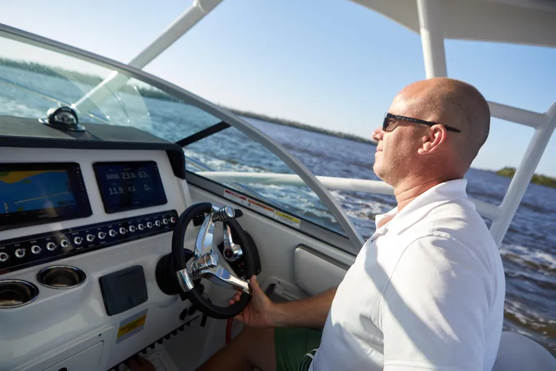 Slide: The Image of Man steering 2024 Finseeker 240 WA boat on open water, sunny day. - 13