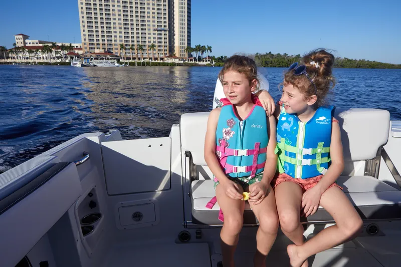Slide: The Image of Two children in life jackets on a 2024 Finseeker 240 WA boat, with waterfront buildings in the background. - 9