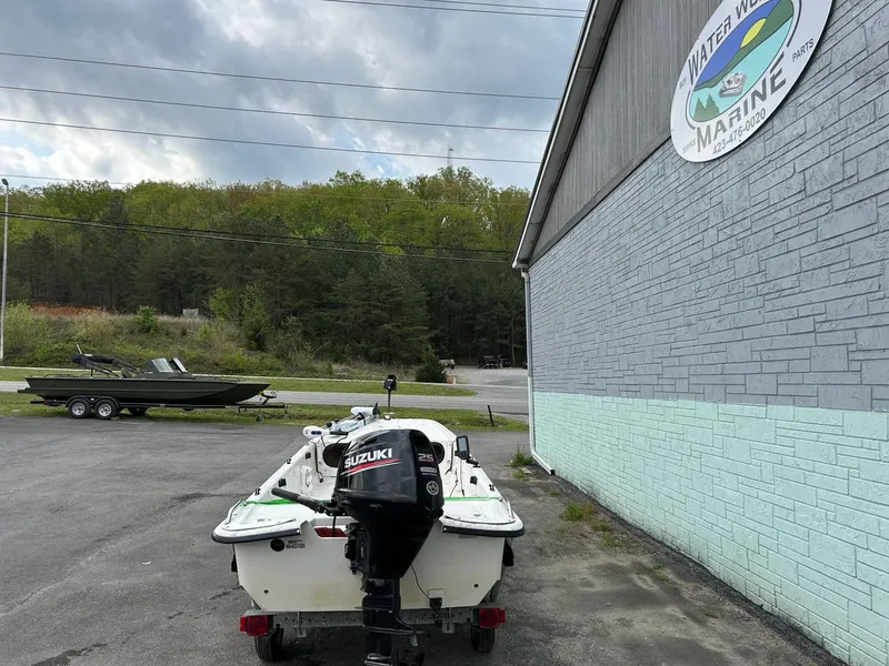 Slide: The Image of 2004 Carolina Skiff J1650 boat with Suzuki motor parked outside a marine shop. - 4