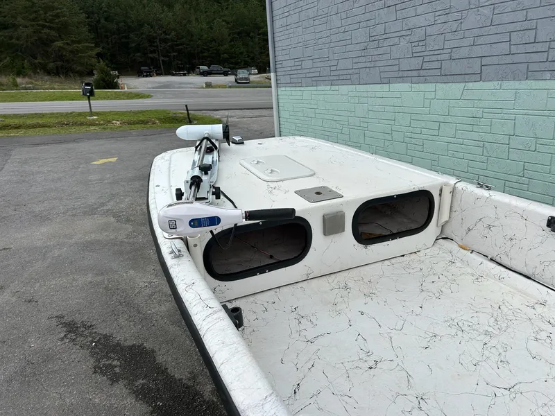 Slide: The Image of 2004 Carolina Skiff J1650 boat parked near a building, featuring a spacious deck. - 5