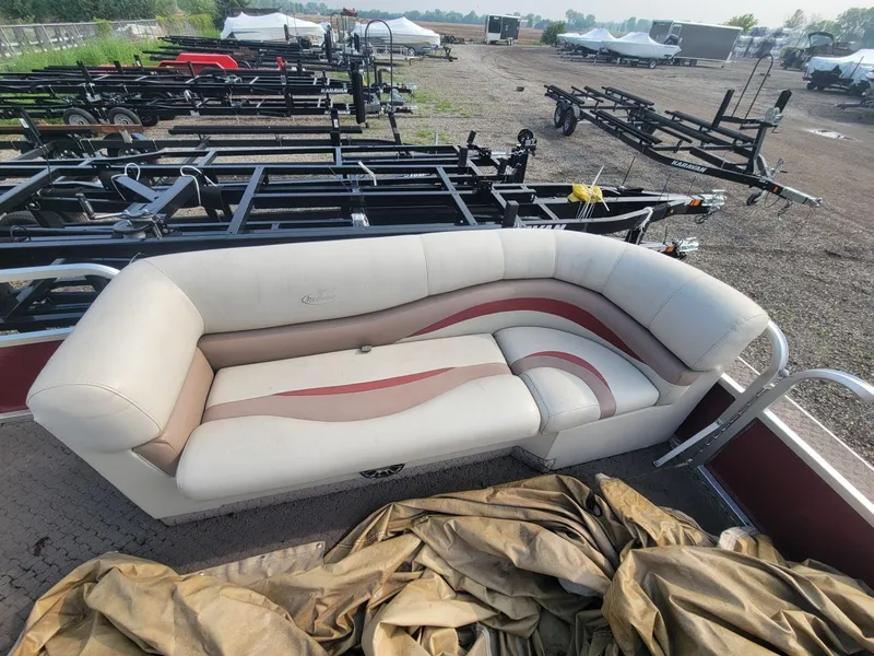 Slide: The Image of 2011 Misty Harbor 2285 DR pontoon boat with cushioned seating and trailers in the background. - 7