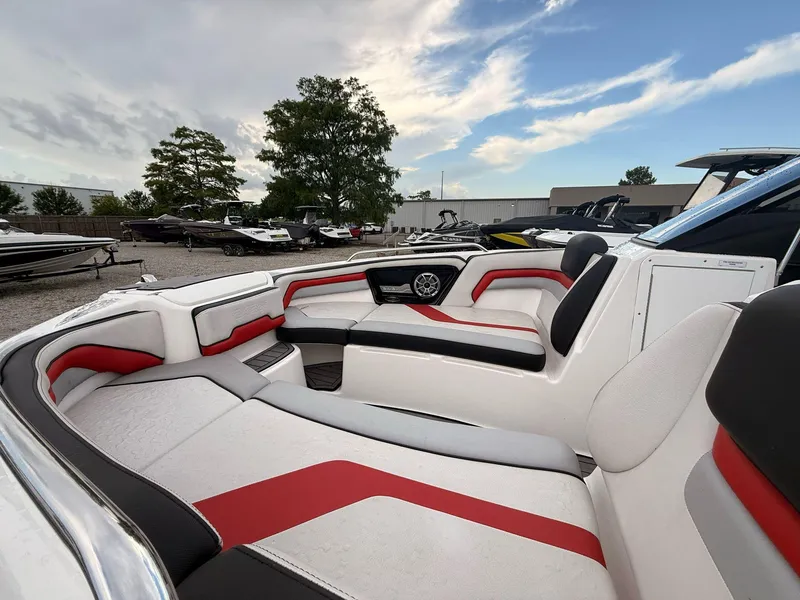Slide: The Image of 2018 Yamaha Boats 242X E-Series interior with red and white seating, parked outdoors. - 6