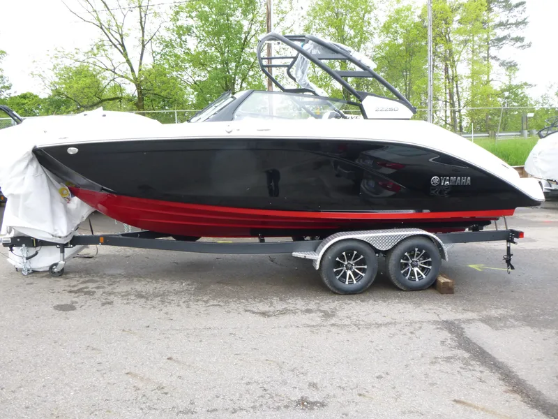 The Image of 2025 Yamaha Boats 222SD on trailer, black and red design, parked outdoors. - 1