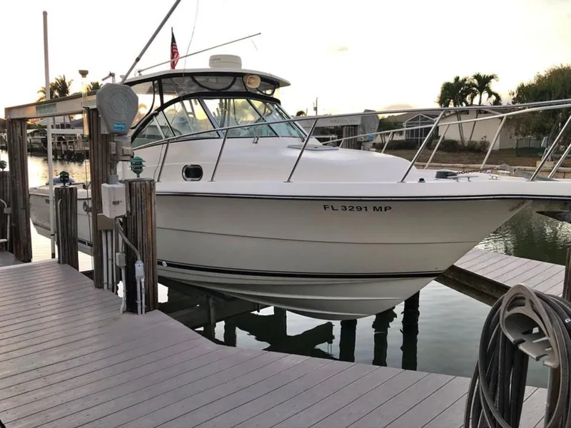 The Image of 2004 Pursuit 3070 Offshore boat docked at marina, surrounded by calm water and palm trees. - 0