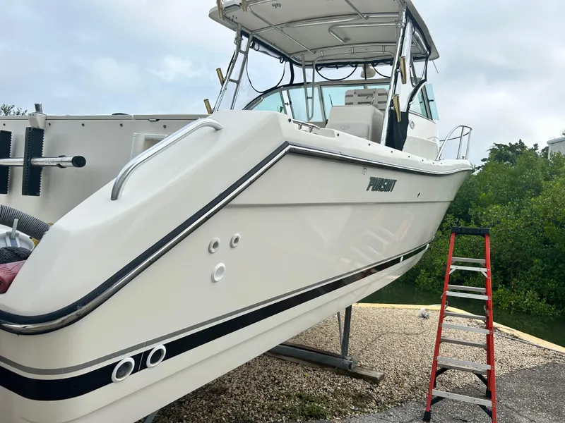 Slide: The Image of 2004 Pursuit 3070 Offshore boat on a stand with a ladder nearby. - 1