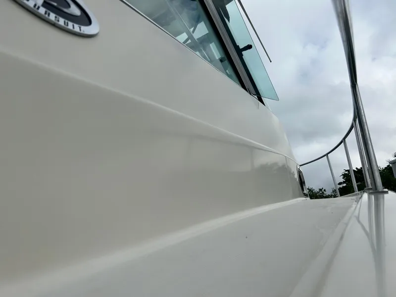 Slide: The Image of 2004 Pursuit 3070 Offshore boat side view with railing and cloudy sky. - 4