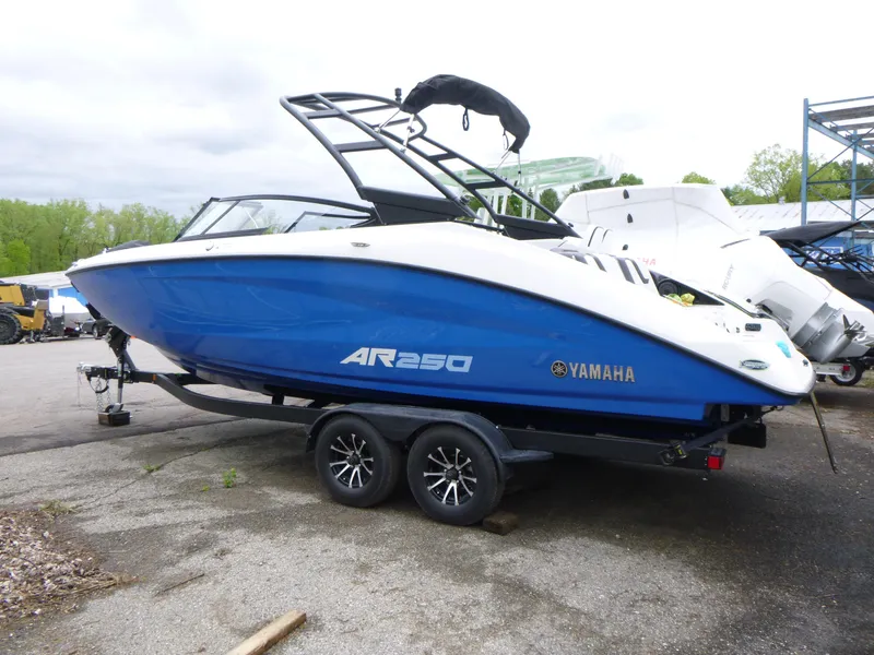 Slide: The Image of 2025 Yamaha Boats AR250 on trailer, blue and white design, parked outdoors. - 1