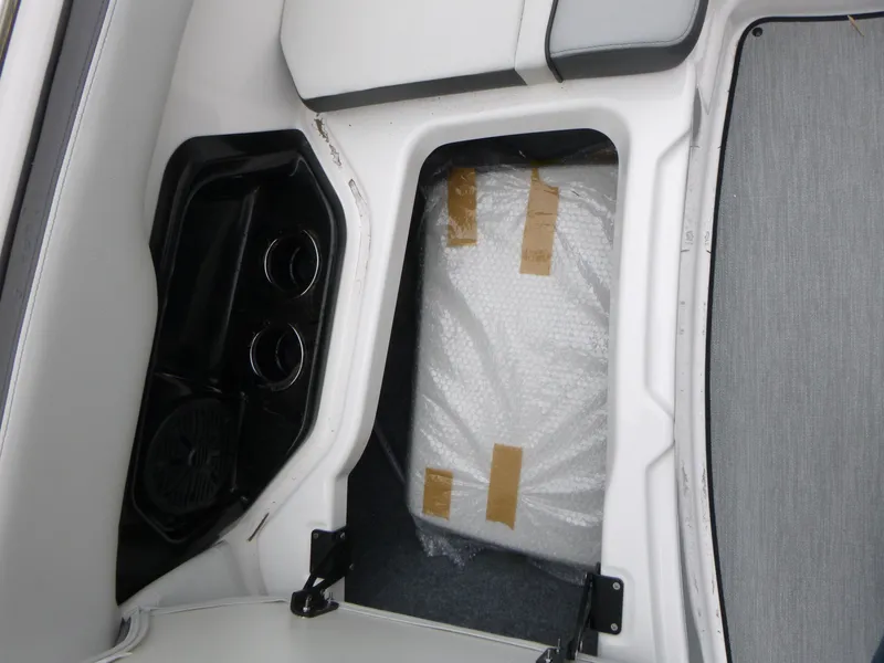 Slide: The Image of 2025 Yamaha Boats AR250 interior storage compartment with cup holders and speaker. - 12