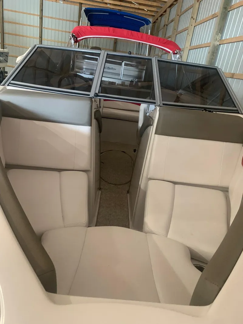 Slide: The Image of 2012 Glastron GLS 195 boat interior with white and gray seating in a storage facility. - 14