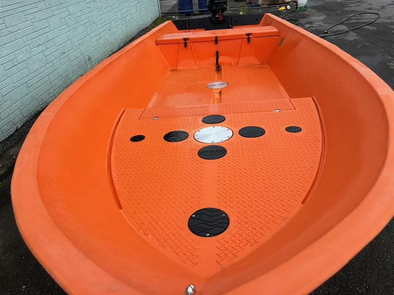 Slide: The Image of 2024 Hog Island Boat Works SW16, bright orange interior, docked on pavement. - 4