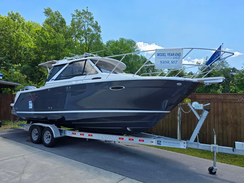 The Image of 2024 Cutwater C-248 Coupe boat on trailer, displayed outdoors with price sign. - 1