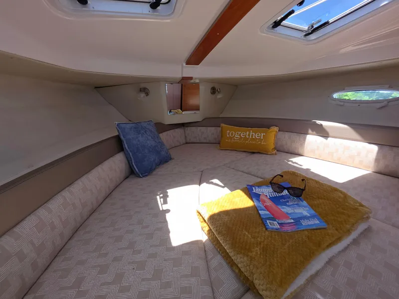 Slide: The Image of 2024 Cutwater C-248 Coupe cabin interior with cozy bedding, pillows, and reading materials. - 10