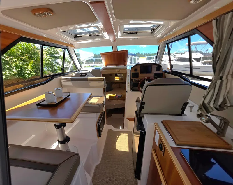Slide: The Image of 2024 Cutwater C-248 Coupe interior with dining area, helm, and panoramic windows. - 12