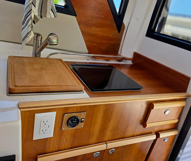 Slide: The Image of 2024 Cutwater C-248 Coupe kitchen area with wooden cabinetry and modern appliances. - 6