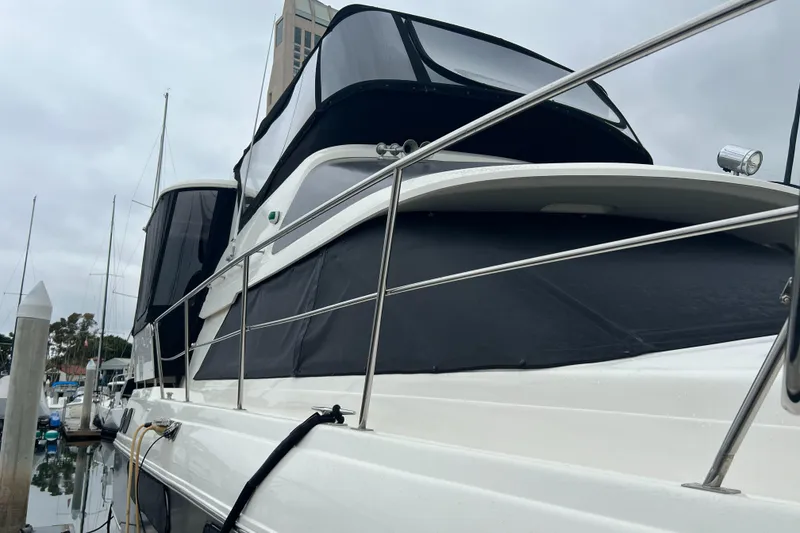 Slide: The Image of 1995 Cruisers Yachts 3650 ACMY docked, featuring sleek design and black canvas covers. - 26