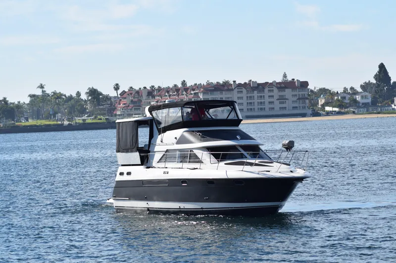 Slide: The Image of 1995 Cruisers Yachts 3650 ACMY on calm water near coastal buildings. - 3