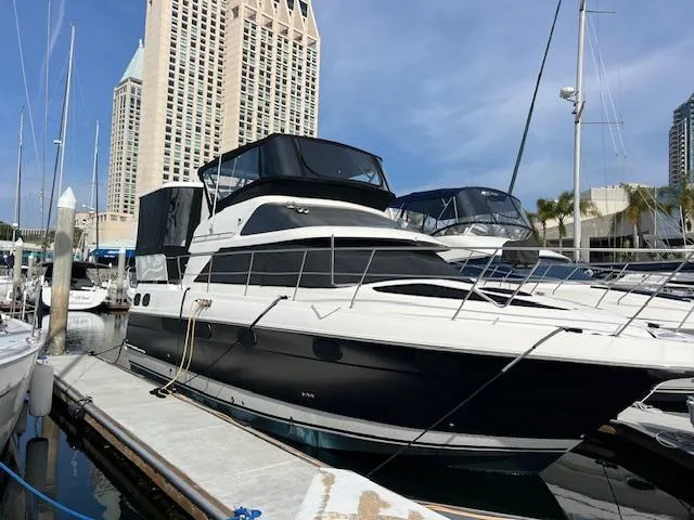 Slide: The Image of 1995 Cruisers Yachts 3650 ACMY docked at marina with cityscape background. - 5