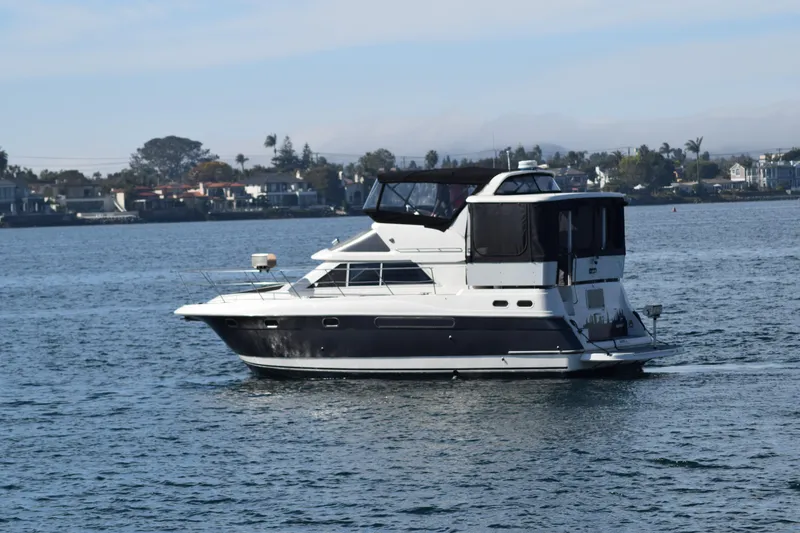 Slide: The Image of 1995 Cruisers Yachts 3650 ACMY on calm water, coastal background. - 6