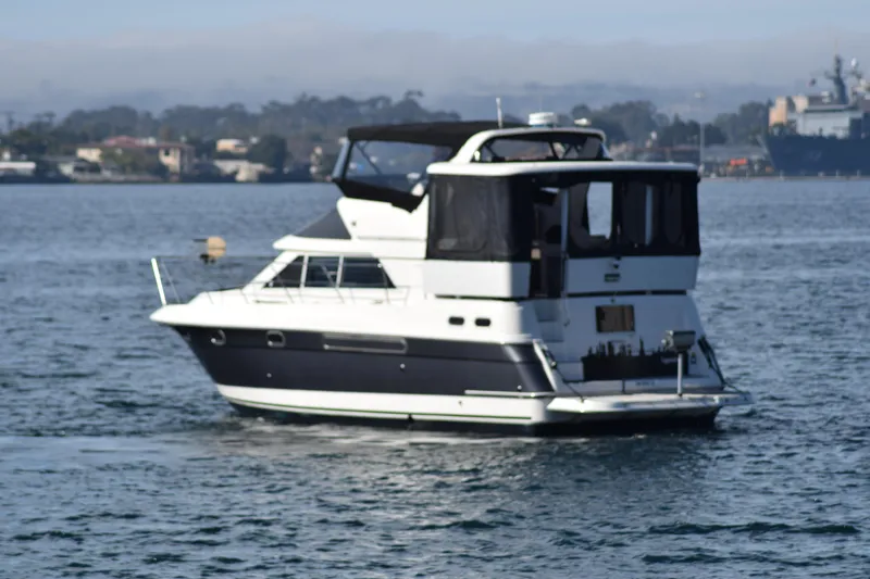 Slide: The Image of 1995 Cruisers Yachts 3650 ACMY on calm water, featuring sleek design and spacious deck. - 7