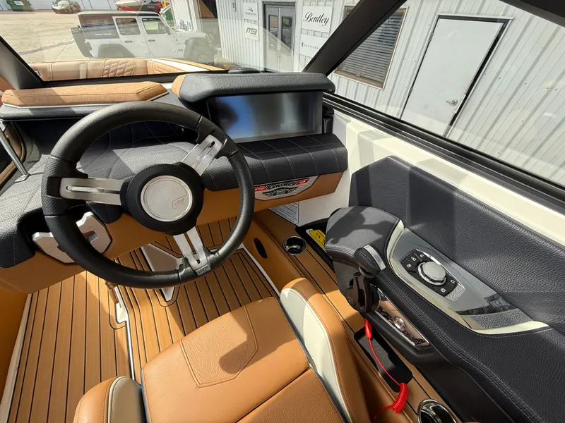 Slide: The Image of 2024 Nautique G21 boat interior with steering wheel, dashboard, and brown leather seats. - 11