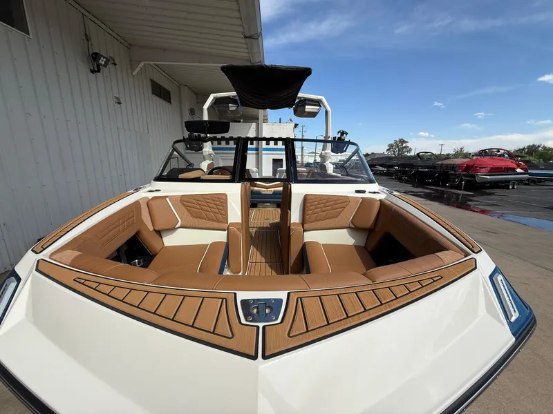 Slide: The Image of 2024 Nautique G21 boat with tan seating, docked outdoors under clear skies. - 2