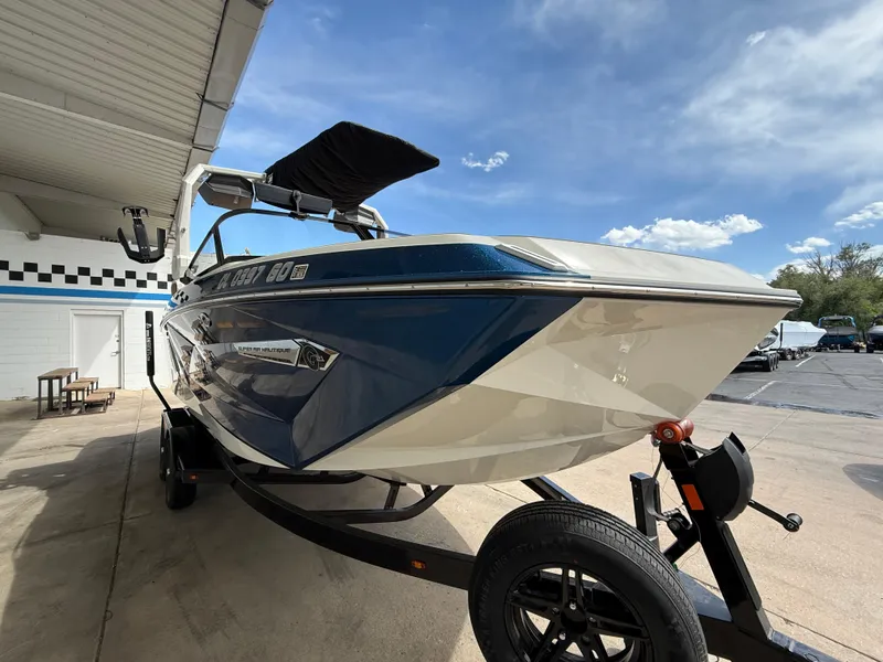 Slide: The Image of 2024 Nautique G21 boat on trailer, blue and white design, parked outdoors under clear sky. - 3