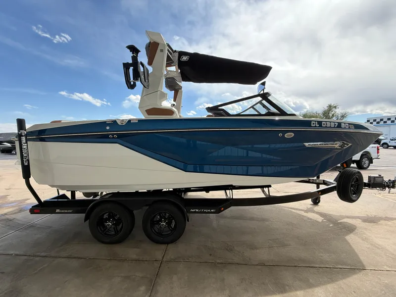 Slide: The Image of 2024 Nautique G21 boat on trailer, blue and white design, parked outdoors. - 4