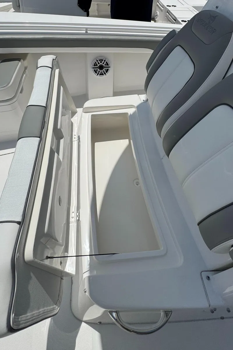 Slide: The Image of 2025 Regulator 28 boat interior with open storage compartment and cushioned seating. - 12