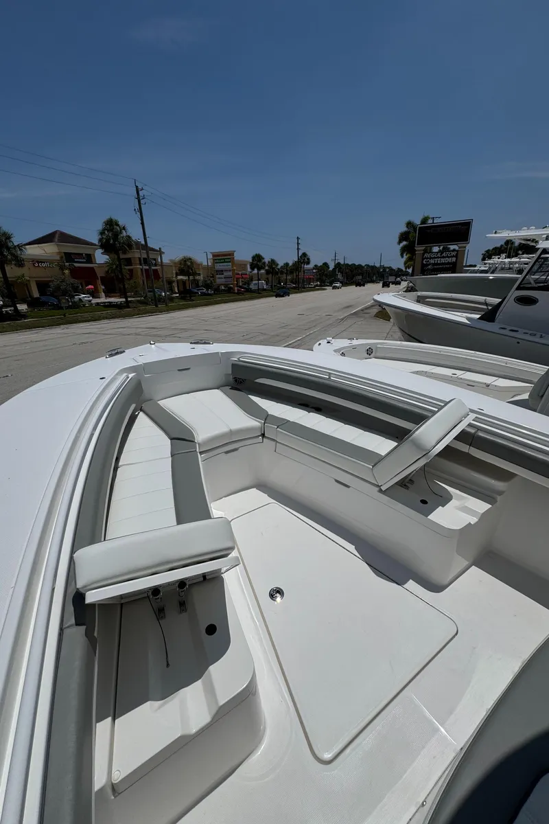Slide: The Image of 2025 Regulator 28 boat interior with seating, parked outdoors under clear sky. - 13