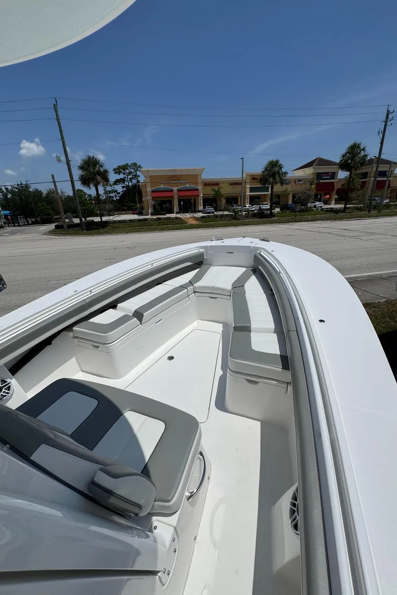Slide: The Image of 2025 Regulator 28 boat with spacious seating, parked near shops under a clear blue sky. - 14