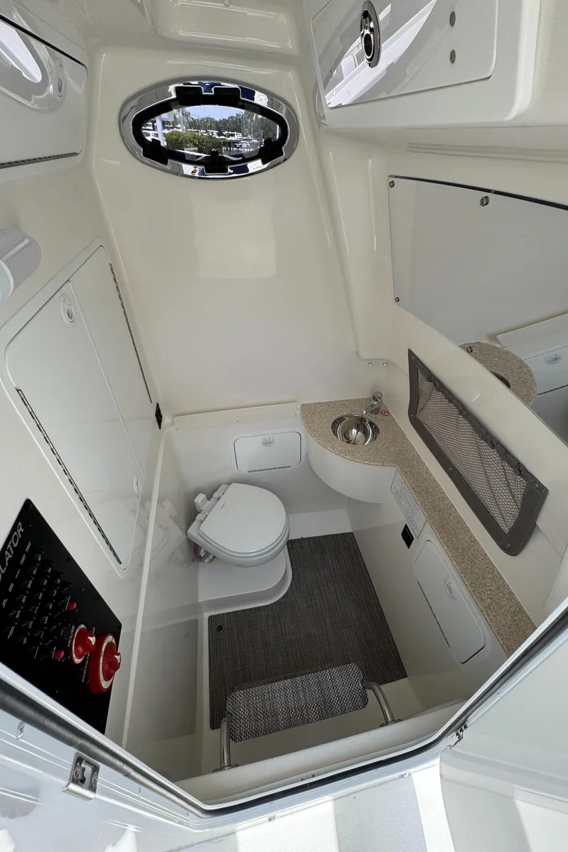 Slide: The Image of 2025 Regulator 28 boat interior with compact bathroom, featuring a toilet, sink, and storage. - 9