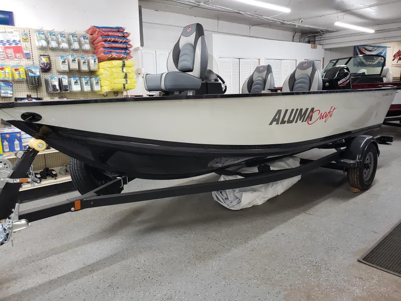 Slide: The Image of 2024 Alumacraft Classic 165cs fishing boat displayed in a showroom. - 0