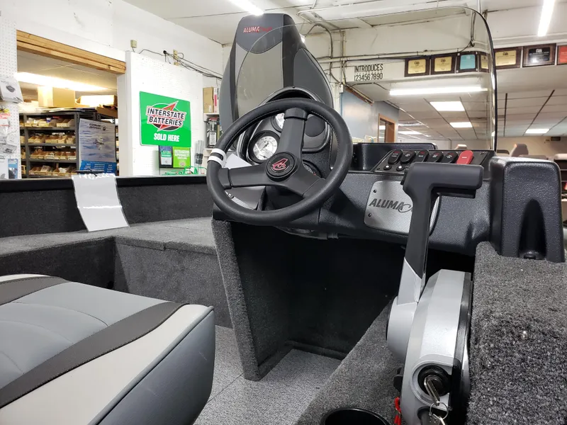 Slide: The Image of 2024 Alumacraft Classic 165cs boat interior with steering wheel and seating. - 4