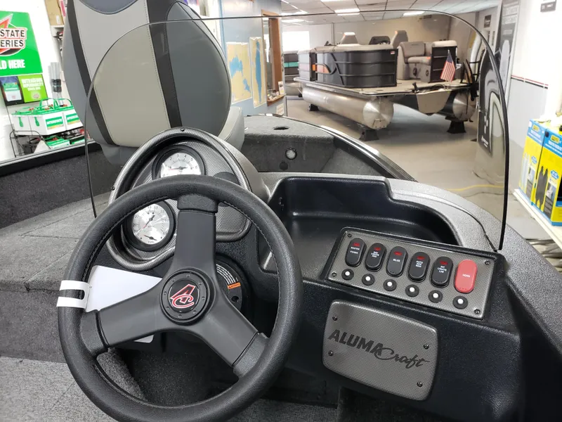 Slide: The Image of 2024 Alumacraft Classic 165cs boat dashboard with steering wheel and control panel. - 5