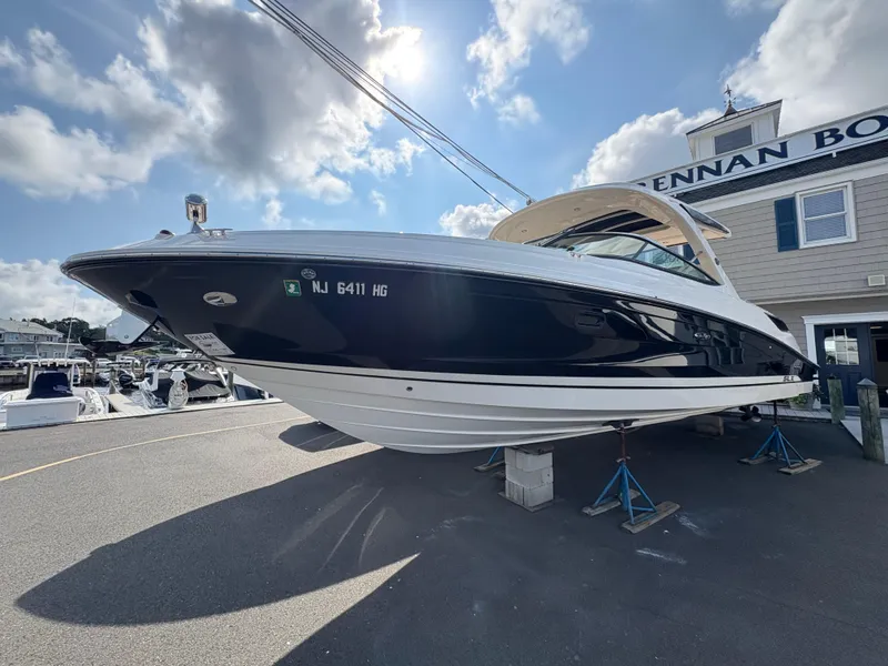 Slide: The Image of 2015 Sea Ray 350 SLX boat on stands, outside a marina building under a partly cloudy sky. - 3