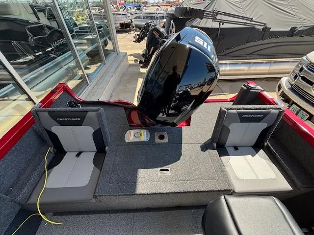 Slide: The Image of 2025 Crestliner 1750 Hawk boat interior with seating and motor, displayed at a dealership. - 3