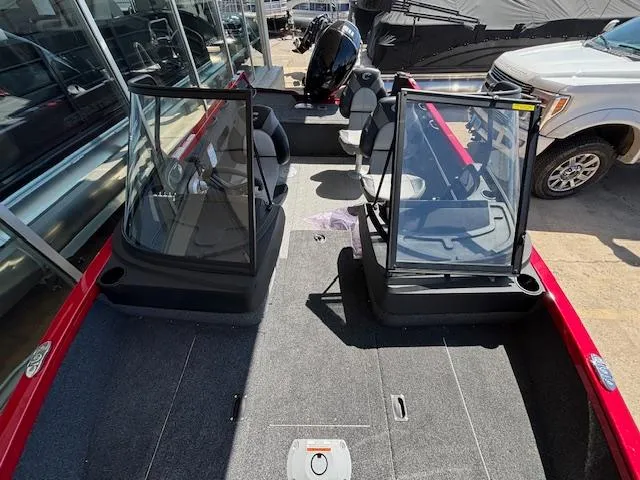 Slide: The Image of 2025 Crestliner 1750 Hawk boat interior with seating and windshield, parked outdoors. - 9