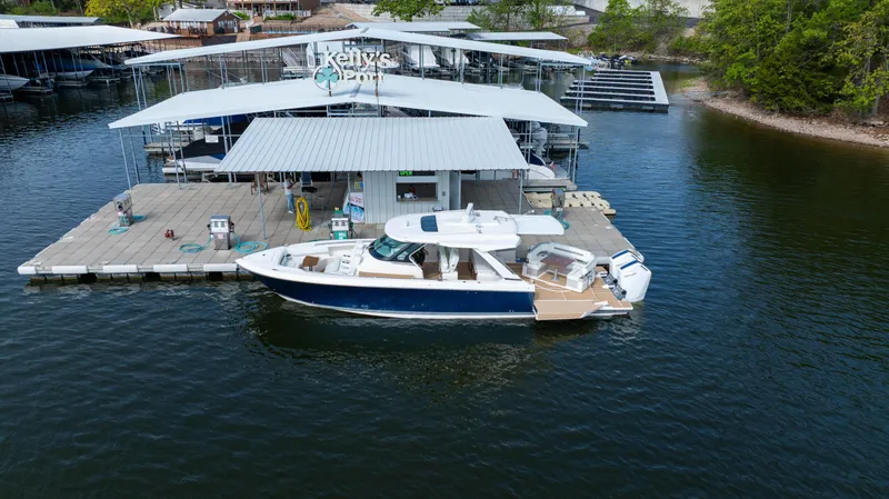 Slide: The Image of 2024 Tiara Yachts 43 LS docked at a marina with covered slips. - 1