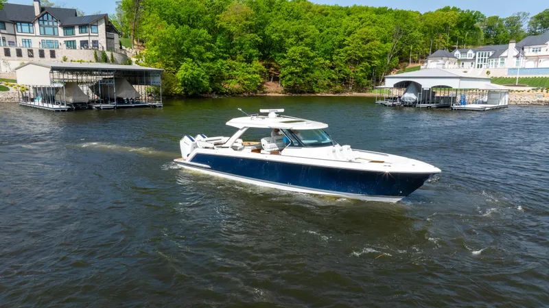 Slide: The Image of 2024 Tiara Yachts 43 LS cruising on a scenic lake near docks and lush greenery. - 18