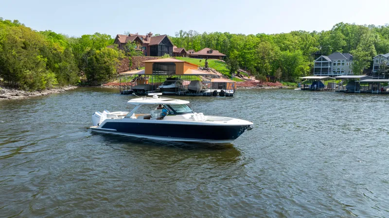 Slide: The Image of 2024 Tiara Yachts 43 LS cruising on a scenic lake near waterfront homes. - 21