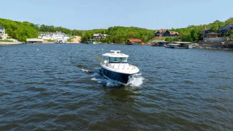 Slide: The Image of 2024 Tiara Yachts 43 LS cruising on a scenic lake with waterfront homes. - 24