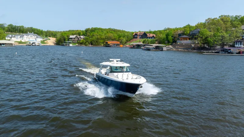 Slide: The Image of 2024 Tiara Yachts 43 LS cruising on a scenic lake with waterfront homes. - 25