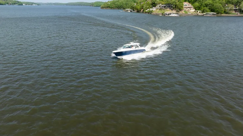 Slide: The Image of 2024 Tiara Yachts 43 LS cruising on a scenic lake with lush shoreline. - 36