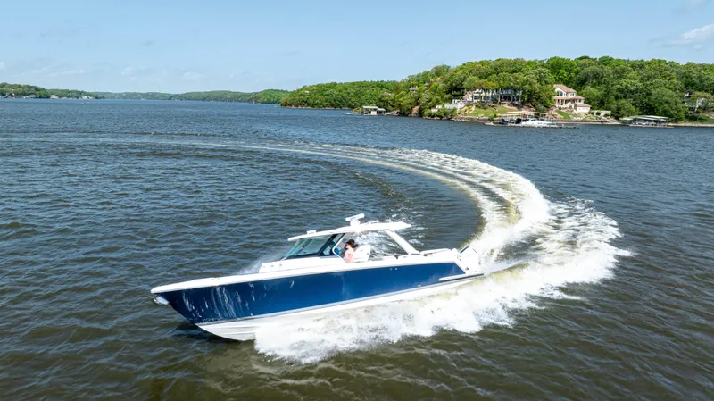 Slide: The Image of 2024 Tiara Yachts 43 LS cruising on a scenic lake with lush green shoreline. - 38