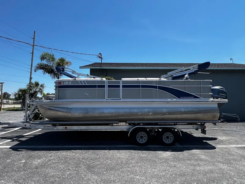 Slide: The Image of 2021 Bennington SX 21 SFXAPG pontoon boat on trailer, parked outdoors. - 2