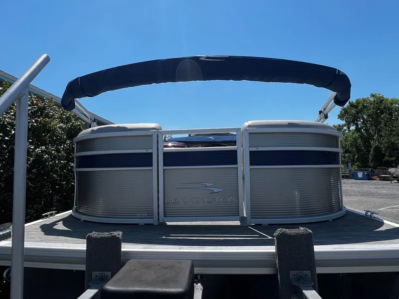 Slide: The Image of 2021 Bennington SX 21 SFXAPG pontoon boat with canopy, parked outdoors under clear blue sky. - 3